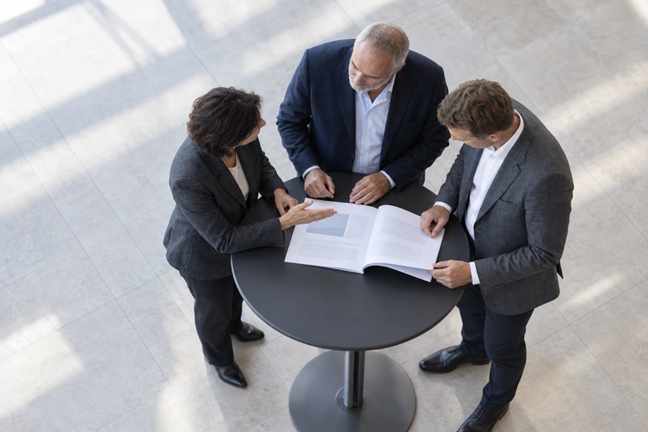 Three colleagues reviewing a report at a standing table